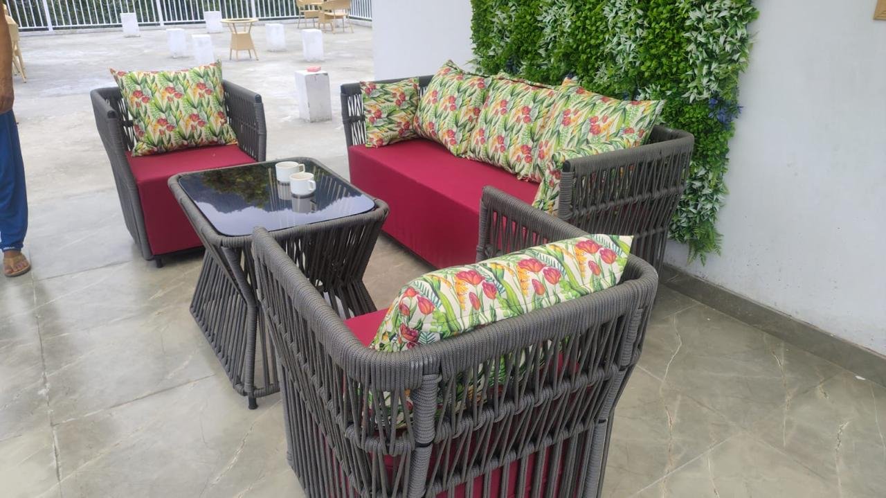 Outdoor Hillside Social seating with grey woven sofa, red cushions, floral pillows, and hill views